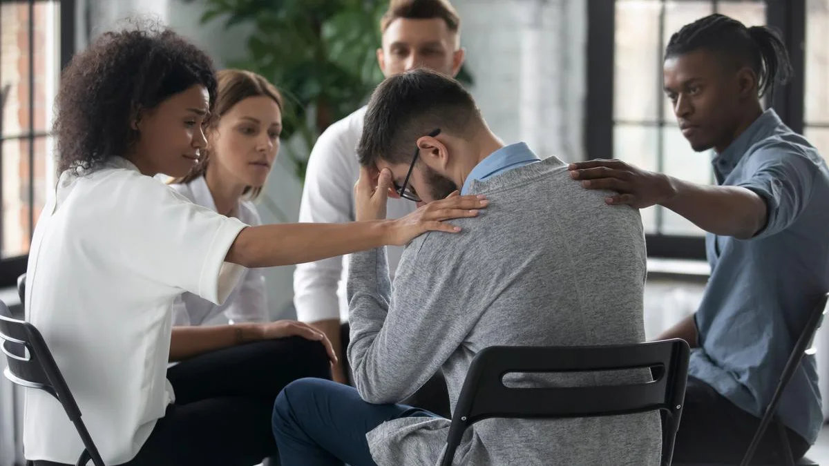 Group of adults sitting in a circle and comforting a man in the circle. Text explains the importance of alcohol rehabilitation
