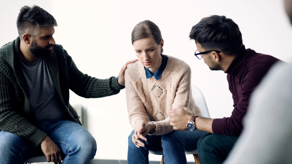 Image of people comforting a woman sitting on a chair. Around 8.4 million adults experience co-occurring disorders.
