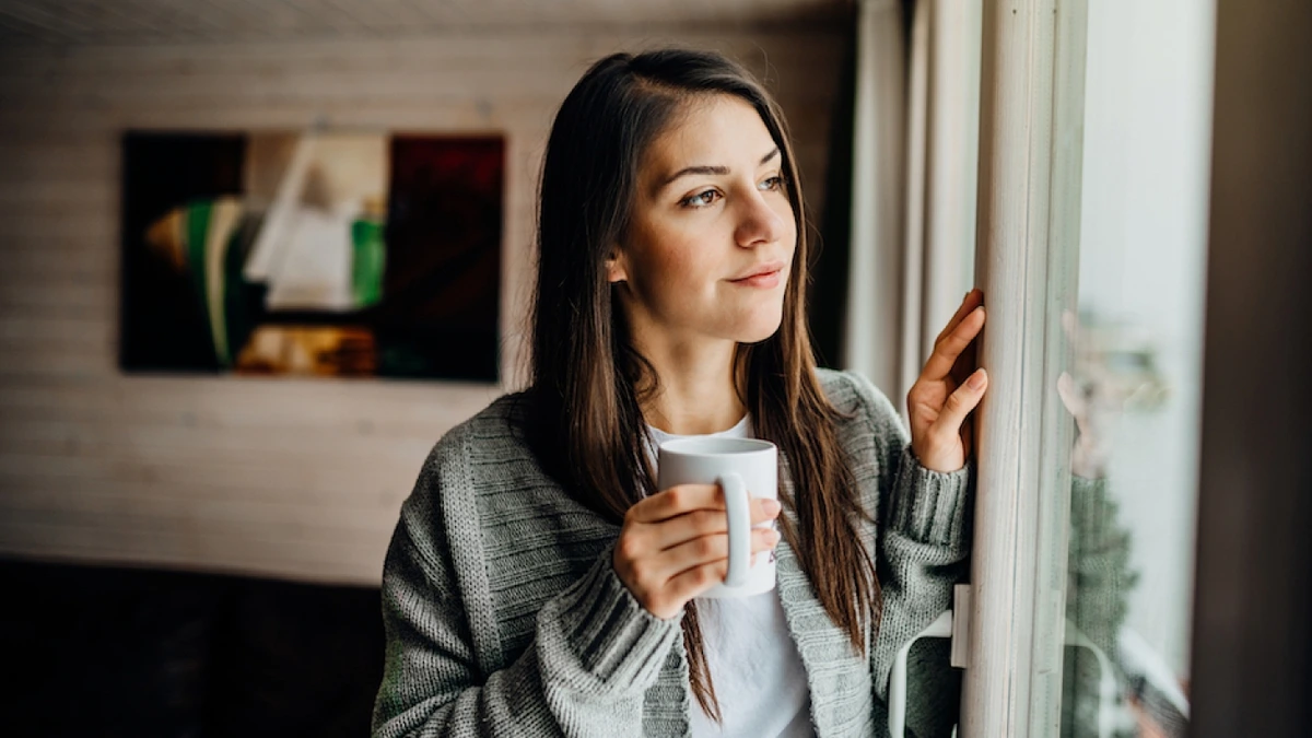 Woman wearing a cardigan and holding a coffee mug. Addiction can worsen existing mental health conditions.