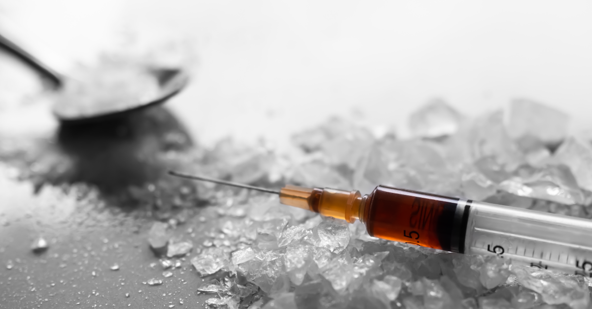 Syringe with red liquid inside on top of a white, crystalline substance.