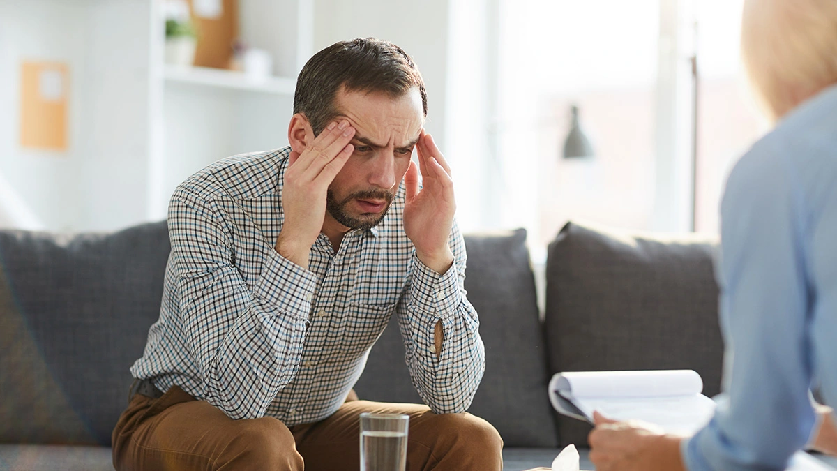 A distressed man clutching head.