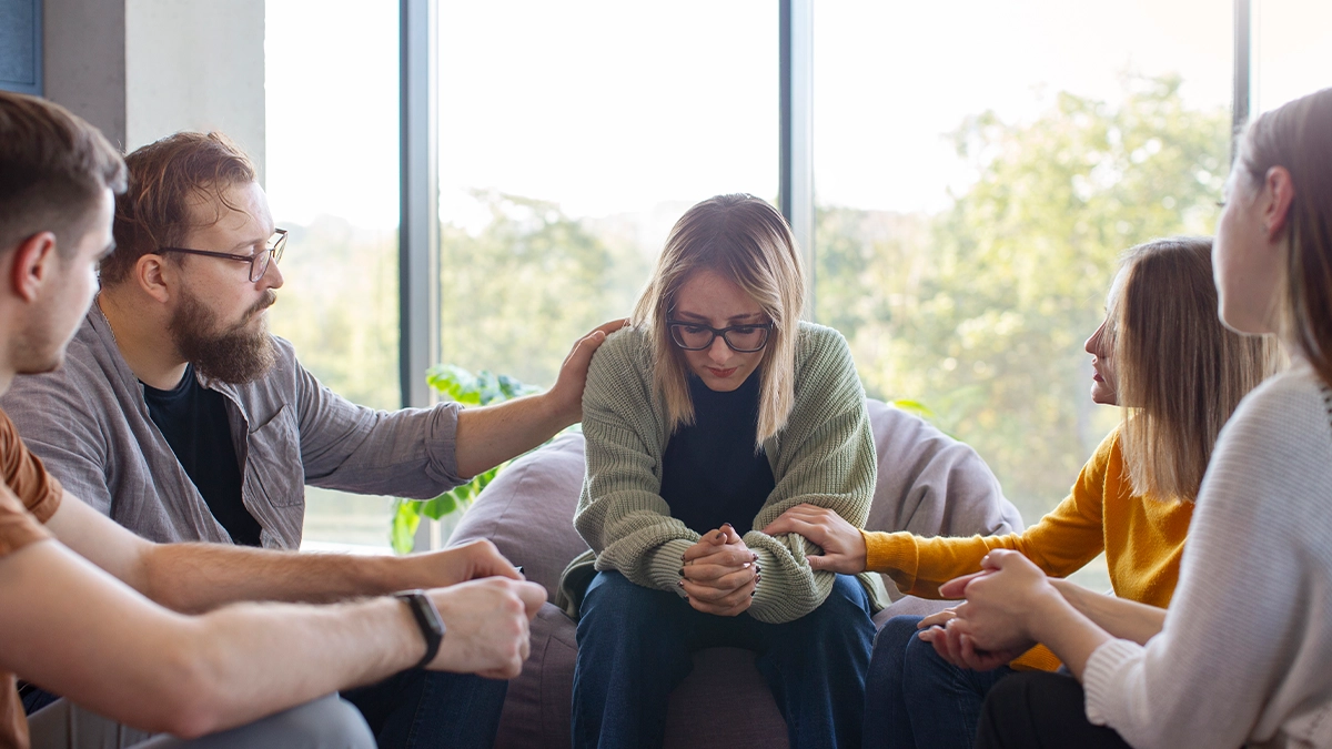 woman being consoled by the group in a group therapy session