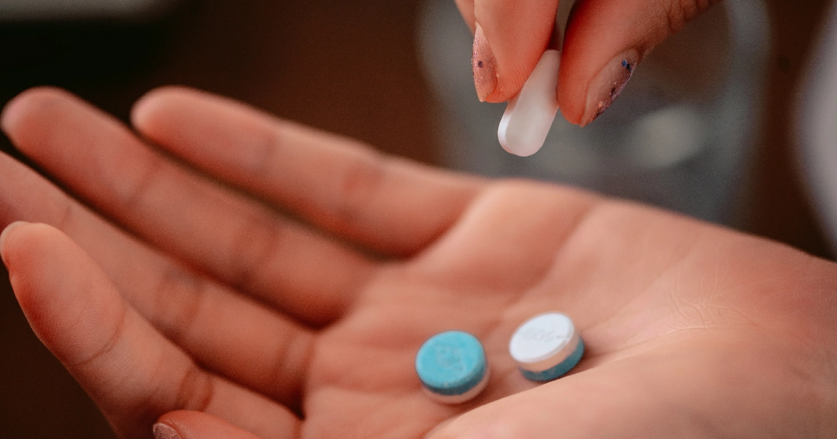 woman's hand with pills being placed onto it